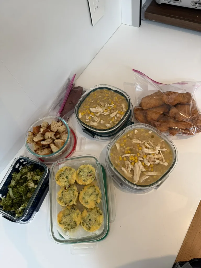 Labeled containers of soup, vegetables, egg bites, croutons, and chicken ready for the fridge