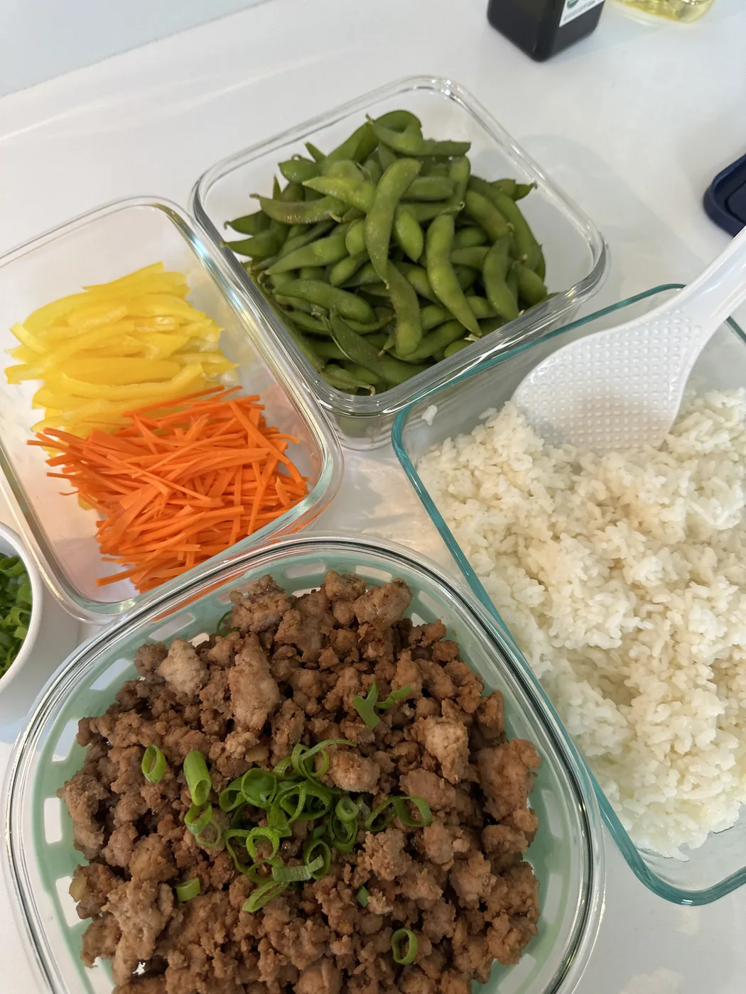 Prepared rice, vegetables, edamame, and seasoned meat ready to assemble into meals