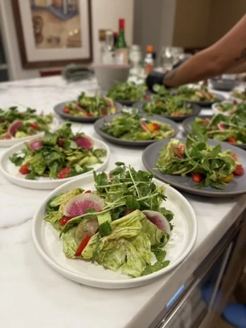Fresh green salads being plated for benefit dinner guests