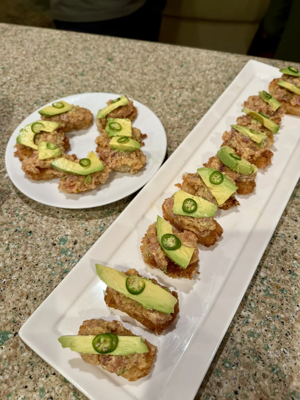 Crispy rice bites topped with avocado and sliced chile